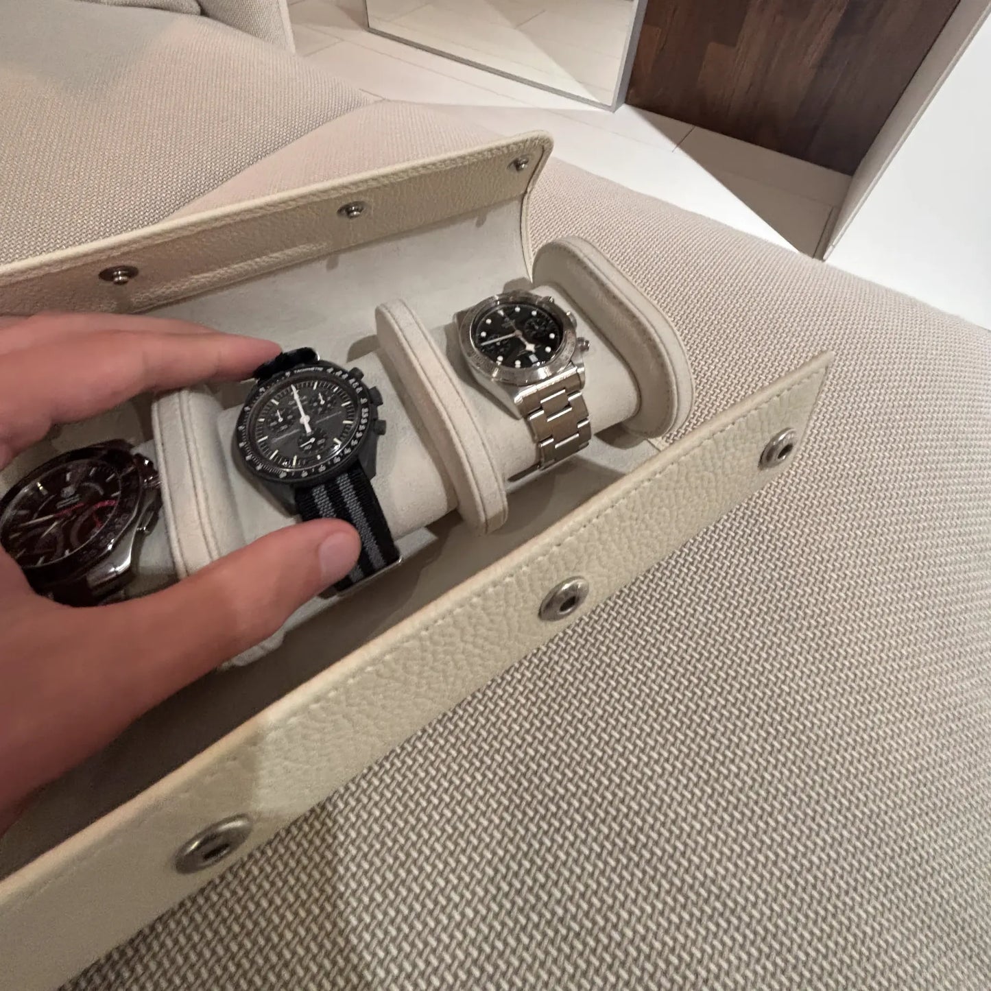 Uhrenrolle ATELIER in Cremeweiß mit drei Armbanduhren bei der Entnahme einer Uhr