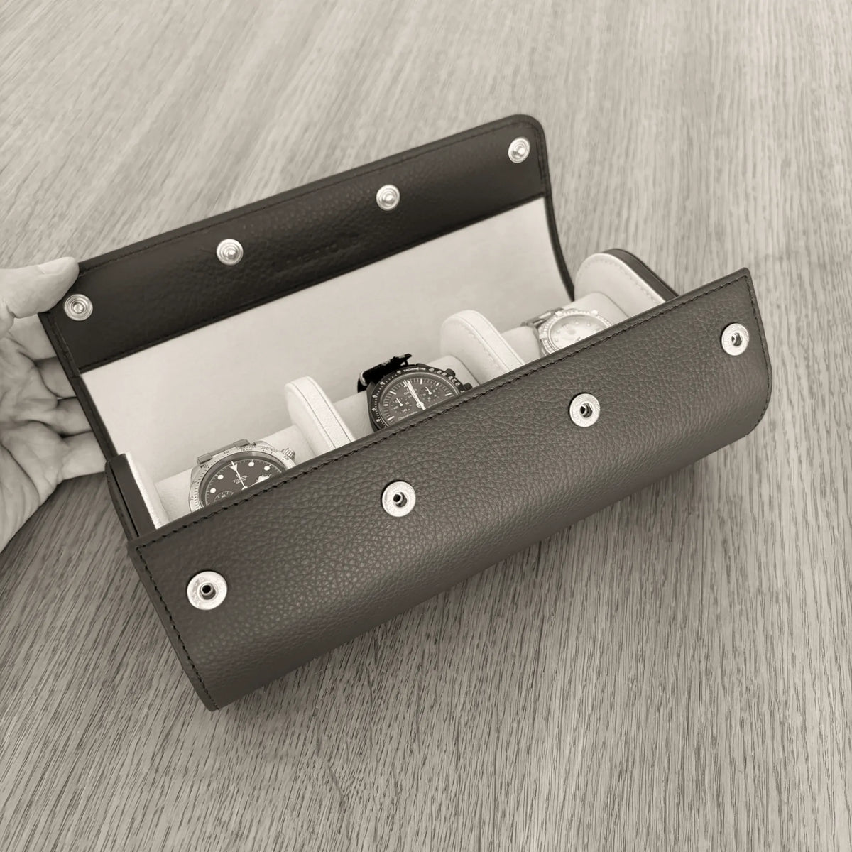 Geöffnete ATELIER Uhrenrolle aus Leder mit drei Uhren auf gepolsterten Uhrenkissen.