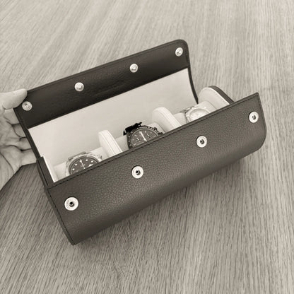 Geöffnete ATELIER Uhrenrolle aus Leder mit drei Uhren auf gepolsterten Uhrenkissen.