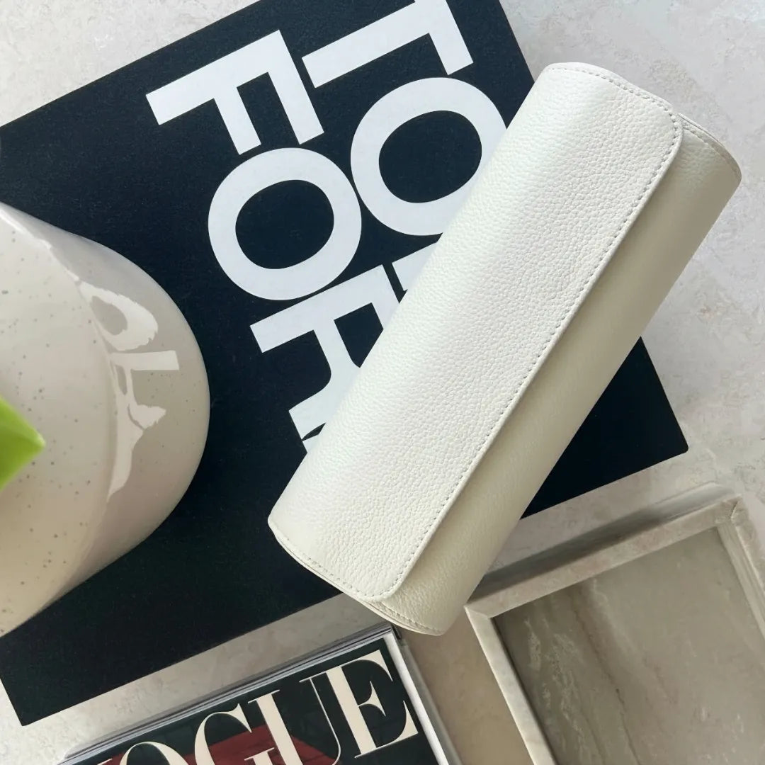 Uhrenrolle „Hamptons“ aus der ATELIER-Kollektion, handgefertigt aus cremeweißem Leder, platziert auf einem Marmoruntergrund neben Designmagazinen.