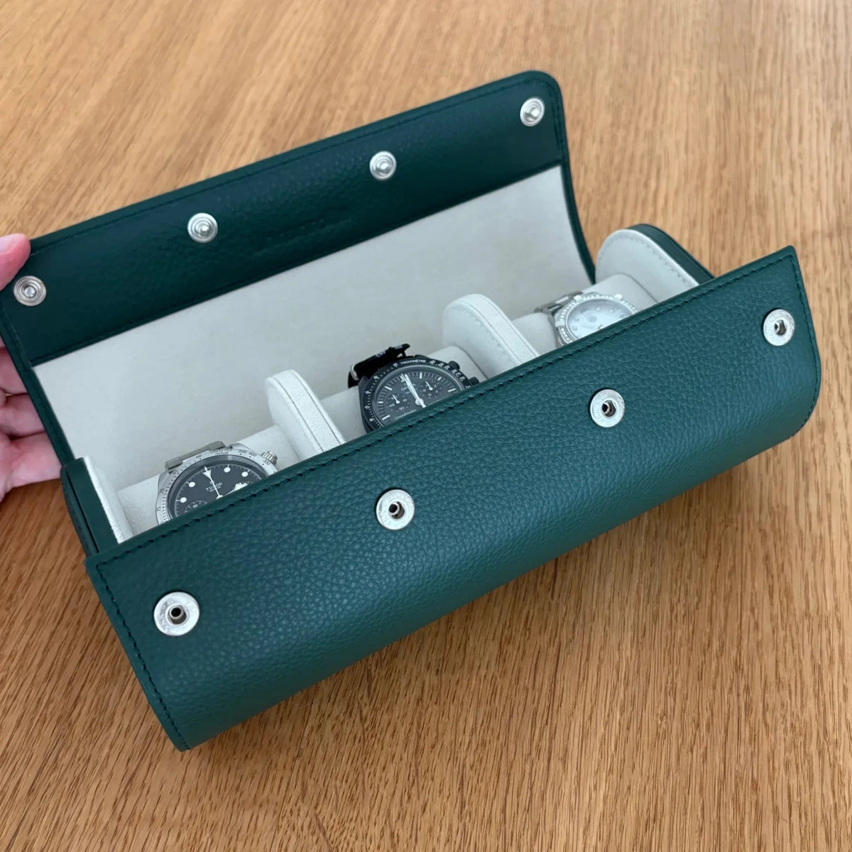 Geöffnete Uhrenrolle ATELIER Oxford aus Leder mit drei Uhren auf gepolsterten Uhrenkissen.