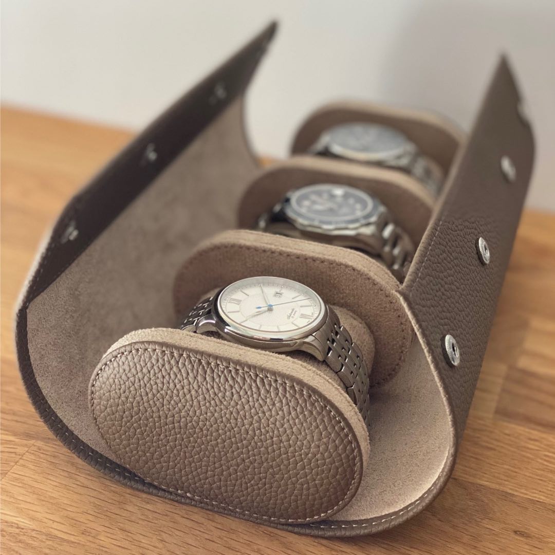 Uhrenrolle SEVILLA aus braunem Leder geöffnet mit 3 Armbanduhren auf Holz.
